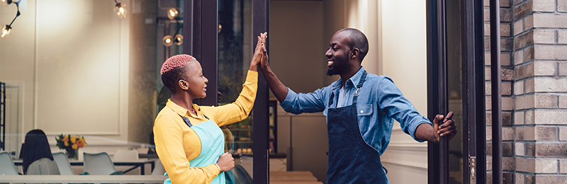 Male and female entrepreneurs high fiving after securing a partnership between their businesses.